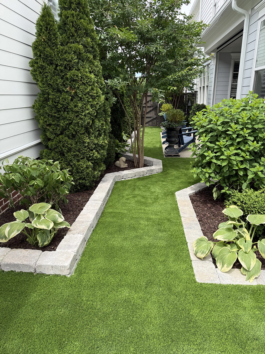 Lush artificial turf lawn with stone borders and manicured beds