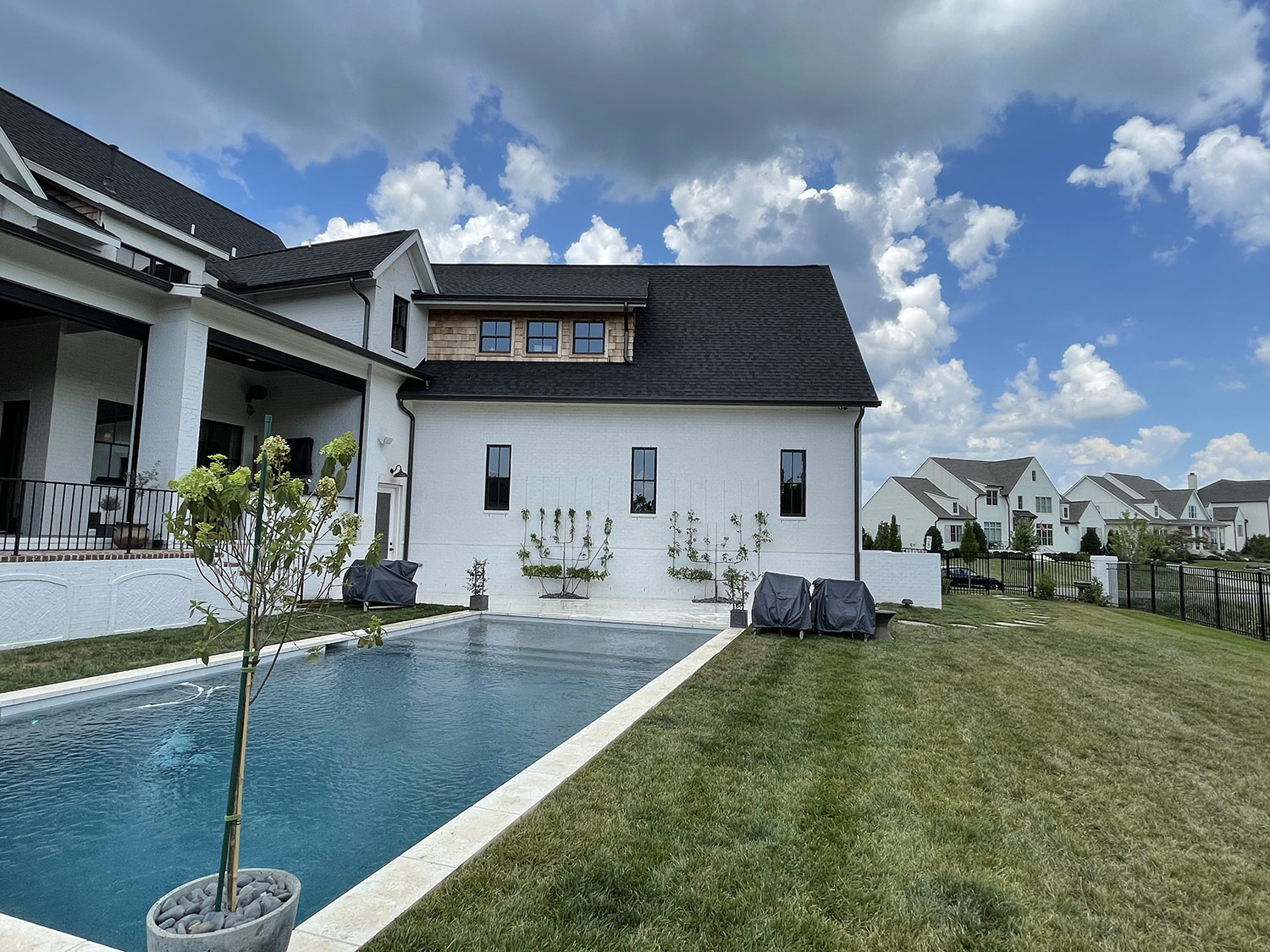 A resort-style pool and manicured lawn beside a modern white-brick home