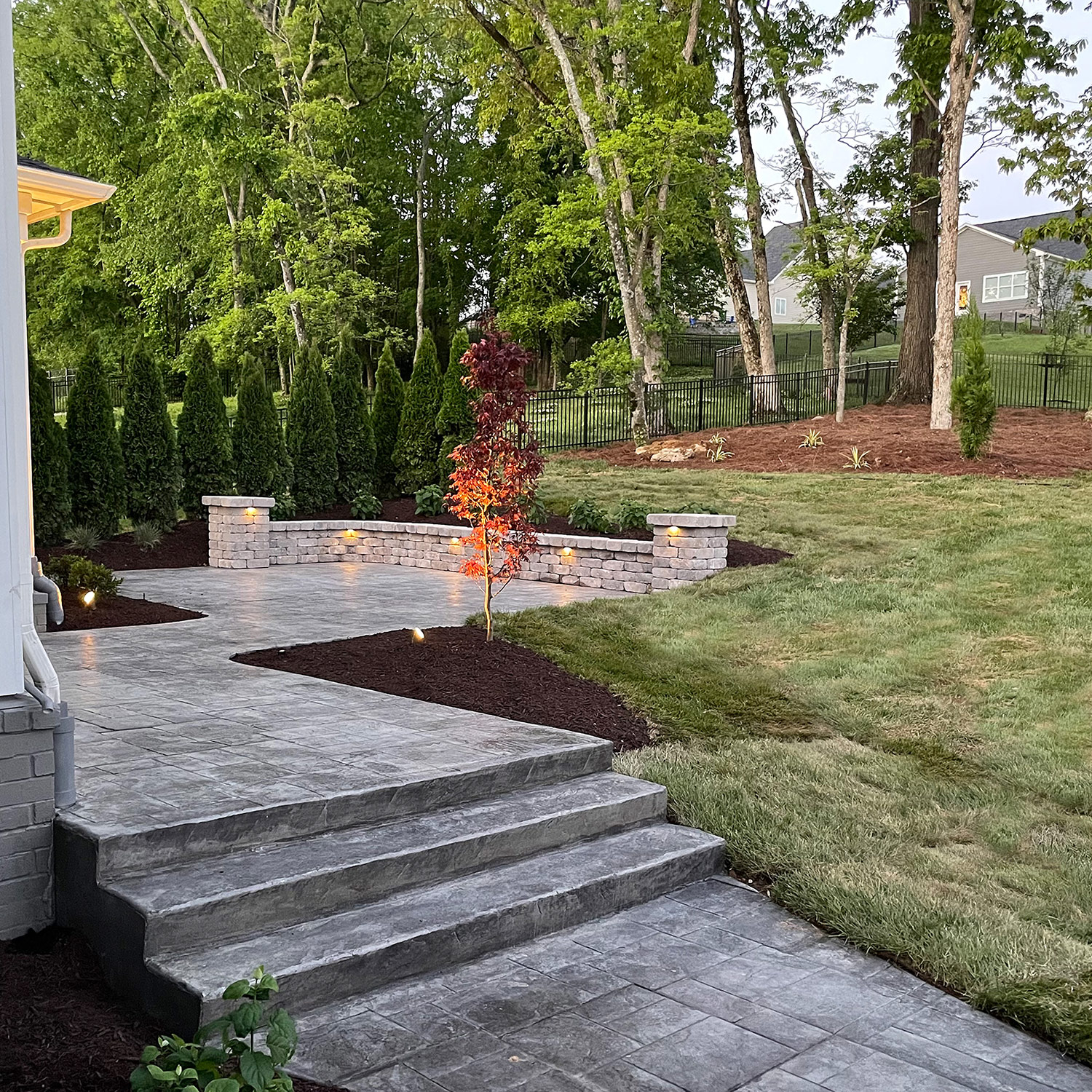 Stamped-concrete steps and a lit retaining wall at dusk